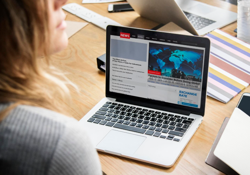 Woman reading online headlines on laptop showing why headlines go viral.