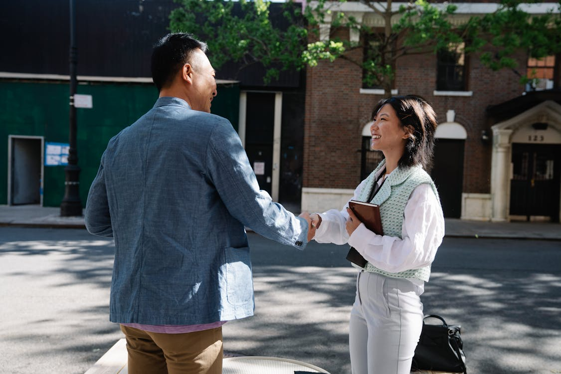 People shaking hands outdoors showing how first impressions are formed.