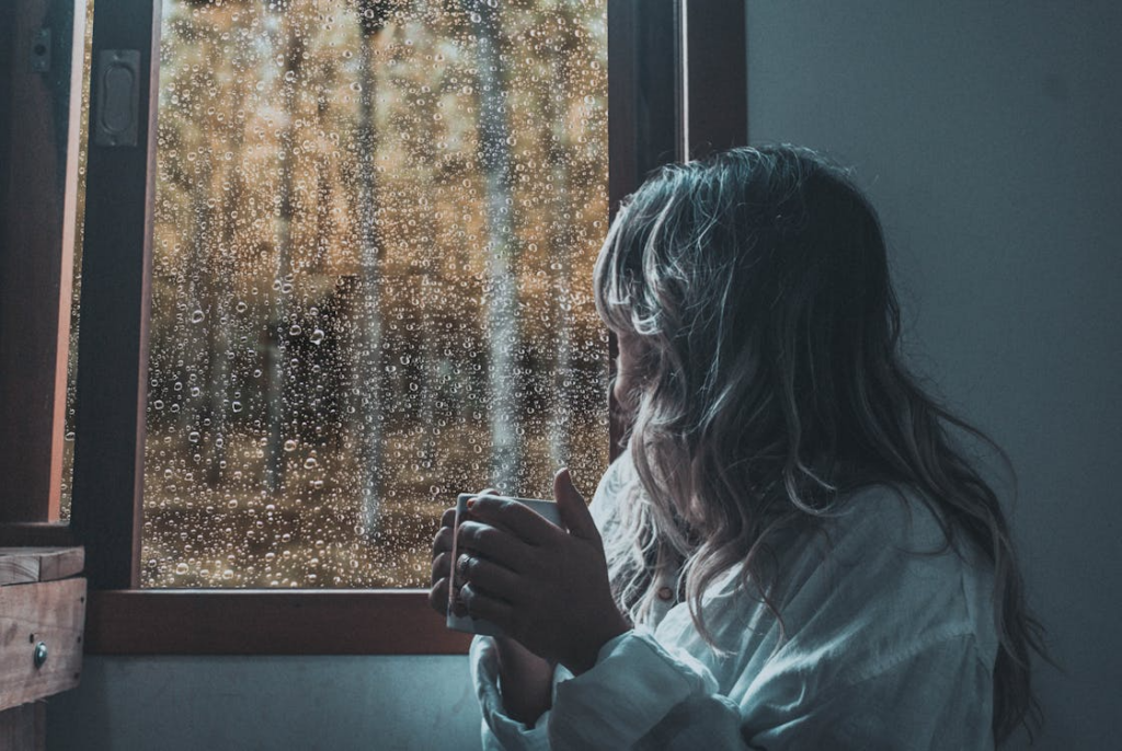 Woman by a rainy window showing how weather affects mood.