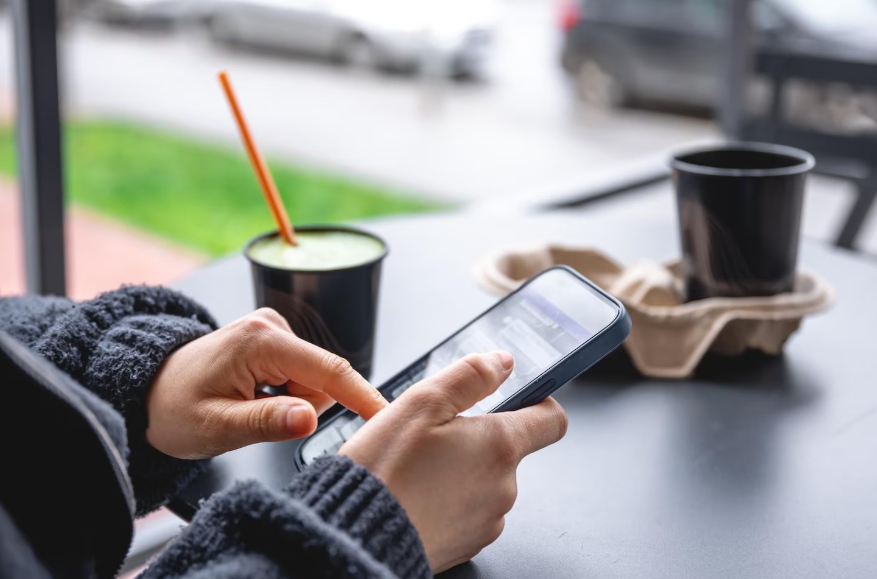 Checking phone while enjoying coffee, showing a simple 5-minute news routine.